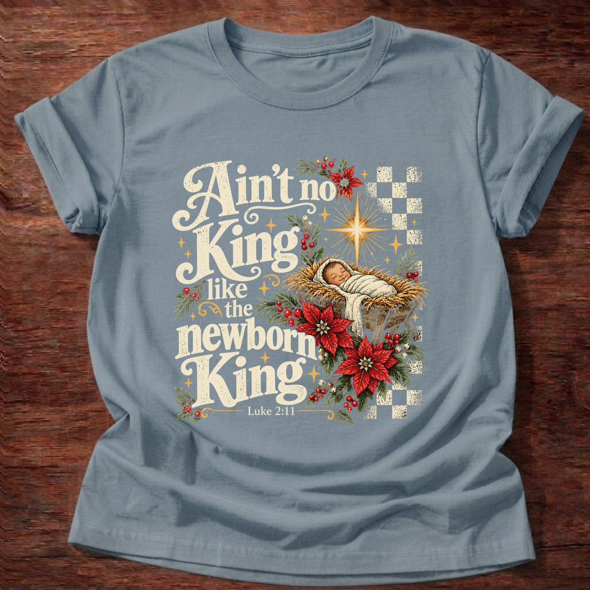 Stone Blue t-shirt printed with a retro manger scene with a star, poinsettias and checkerboard graphic and “Ain't no King like the newborn King.” Luke 2:11 Christian shirt