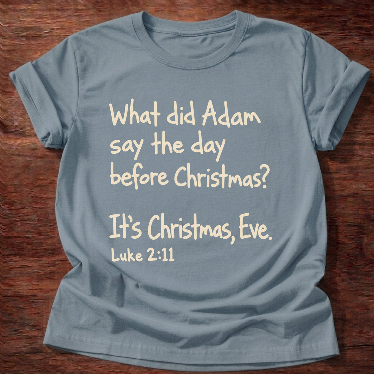 Stone Blue t-shirt printed with a simple hand-lettered Bible joke graphic and “What did Adam say the day before Christmas? It's Christmas, Eve.” Luke 2:11 Christian shirt