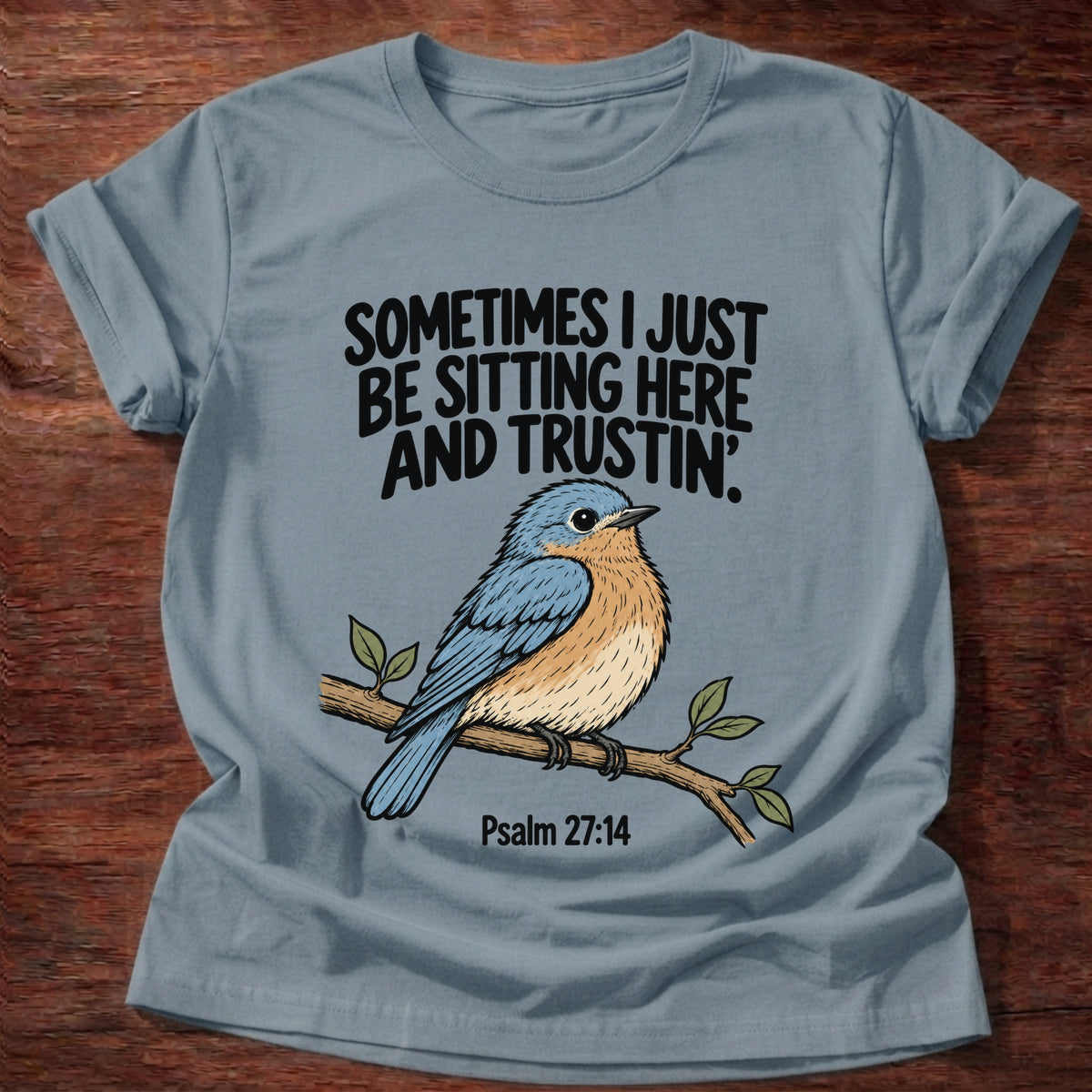 Stone Blue t-shirt printed with a bluebird on a branch graphic and 'Sometimes I just be sitting here and trustin'.' Psalm 27:14 faith based gift