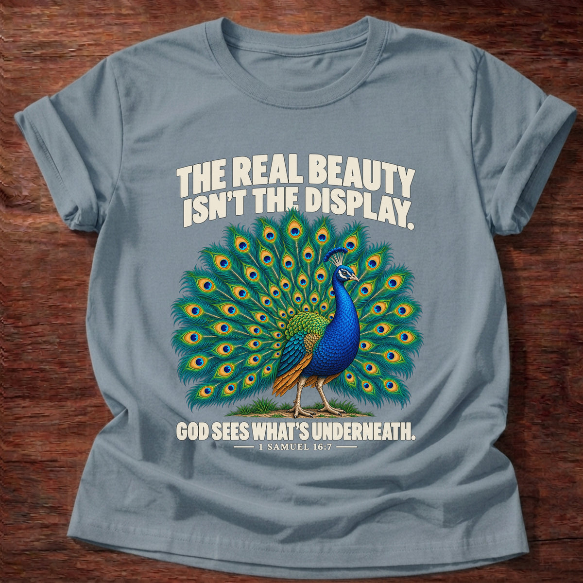 Stone Blue t-shirt printed with a peacock with feathers in full display graphic and 'The real beauty isn't the display. God sees what's underneath.' 1 Samuel 16:7 faith based gift