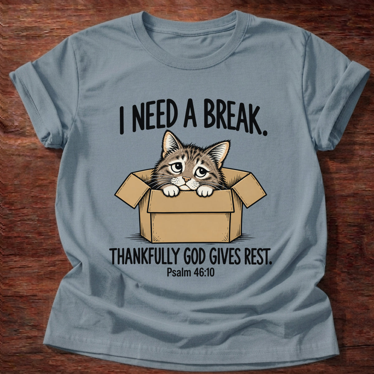 Stone Blue t-shirt printed with a cat curled in a cardboard box graphic and 'I need a break. Thankfully God gives rest.' Psalm 46:10 faith based gift
