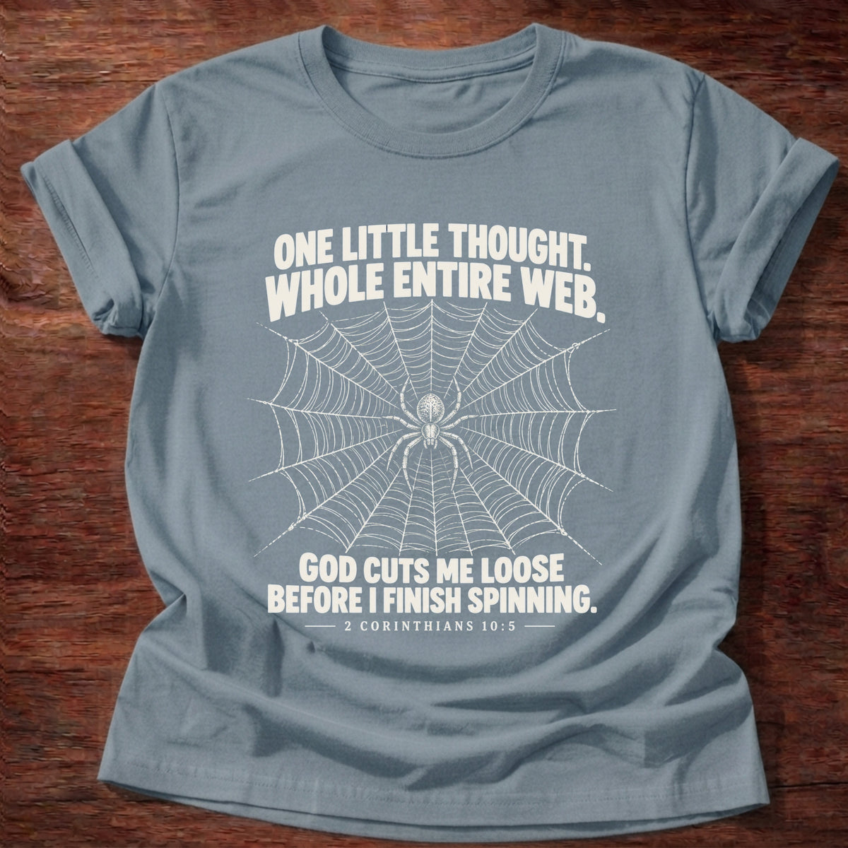 Stone Blue t-shirt printed with a spider at the center of its web graphic and 'One little thought. Whole entire web. God cuts me loose before I finish spinning.' 2 Corinthians 10:5 faith based gift
