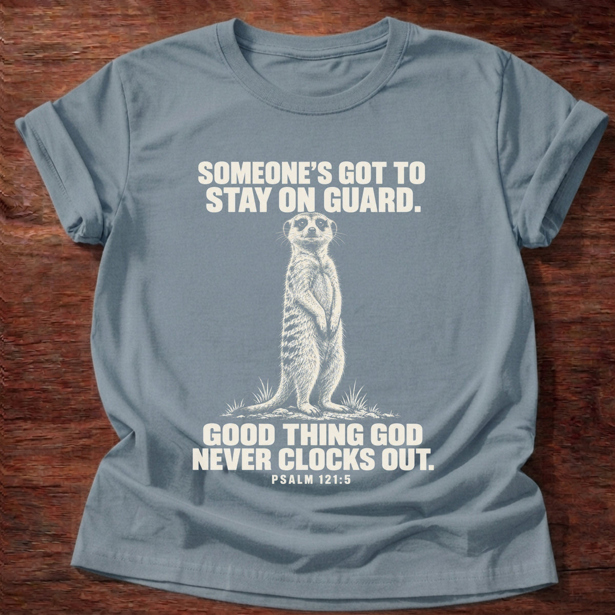 Stone Blue t-shirt printed with a meerkat standing guard on lookout graphic and 'Someone's got to stay on guard. Good thing God never clocks out.' Psalm 121:5 faith based gift