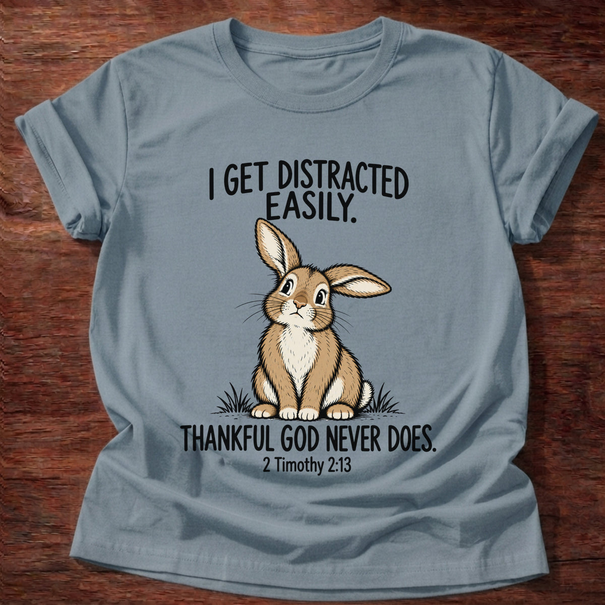 Stone Blue t-shirt printed with a rabbit graphic and 'I get distracted easily. Thankful God never does.' 2 Timothy 2:13 faith based gift