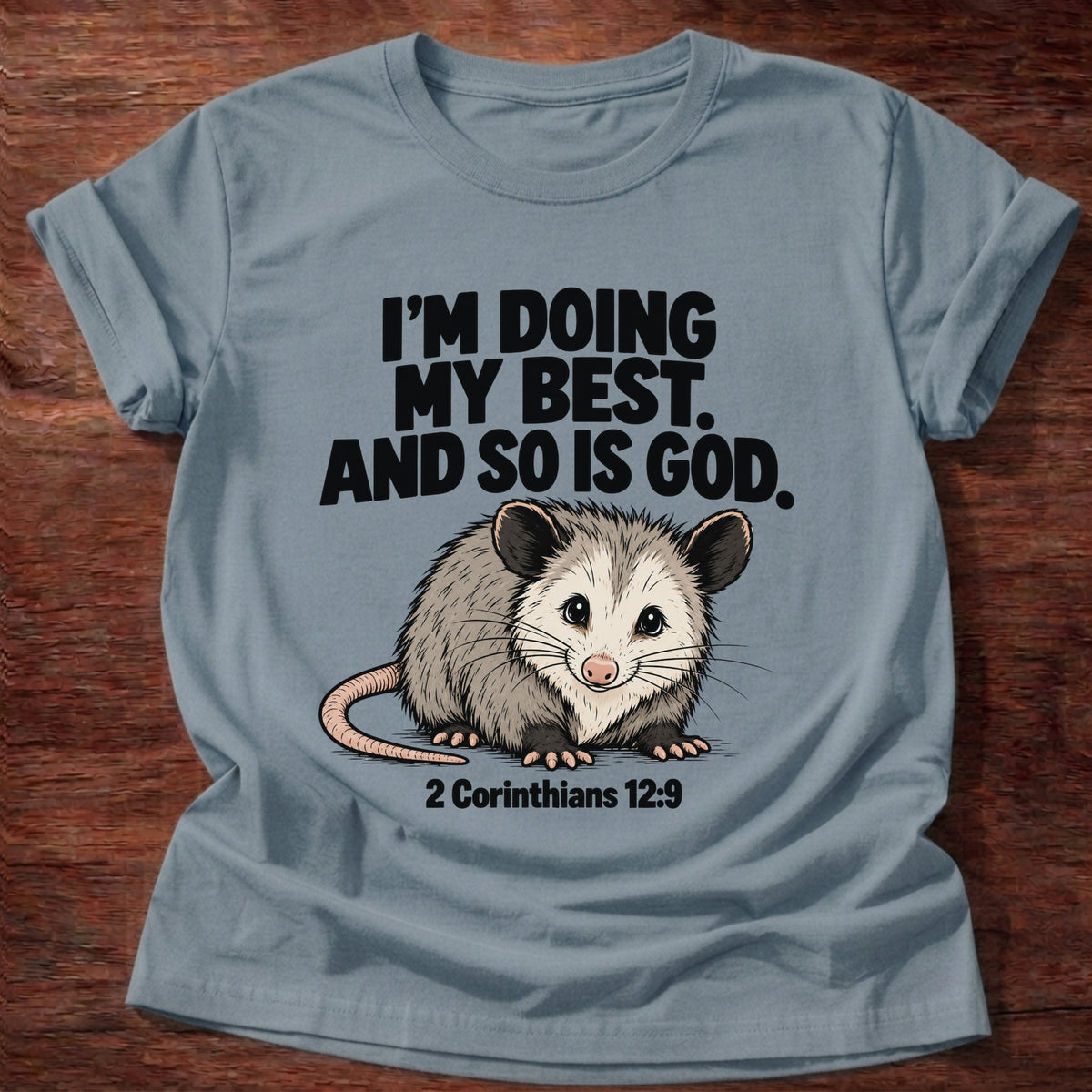 Stone Blue t-shirt printed with an opossum graphic and 'I'm doing my best. And so is God.' 2 Corinthians 12:9 faith based gift