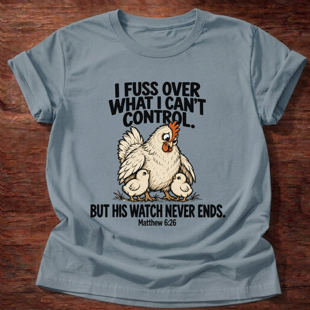 Stone Blue t-shirt printed with a fussing hen graphic and 'I fuss over what I can't control. But His watch never ends.' Matthew 6:26 faith based gift