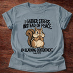 Stone Blue t-shirt printed with a squirrel gathering acorns graphic and 'I gather stress instead of peace. I'm learning contentment.' Luke 12:15 faith based gift