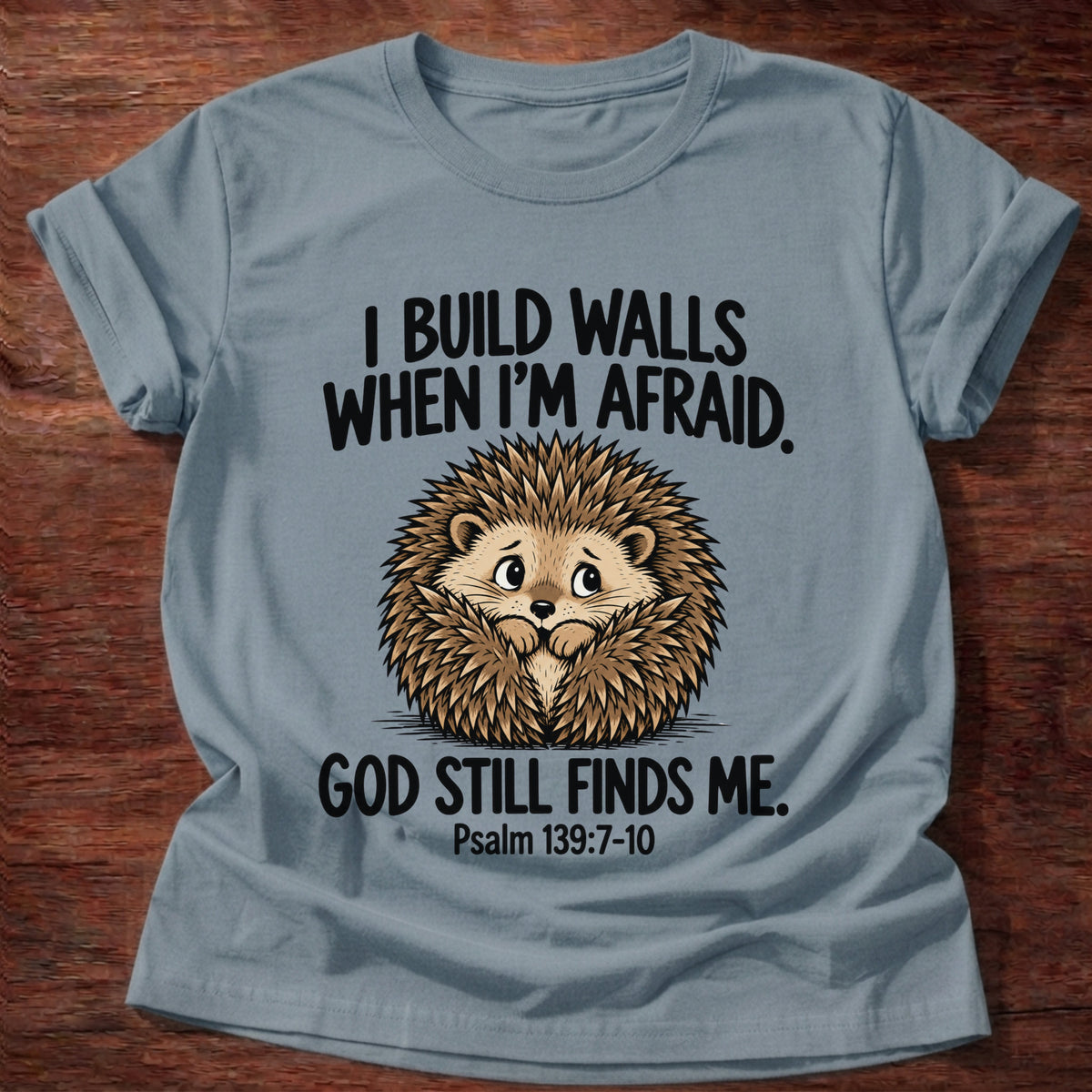 Stone Blue t-shirt printed with a hedgehog curled into a ball and 'I build walls when I'm afraid. God still finds me.' Psalm 139:7-10 faith based gift