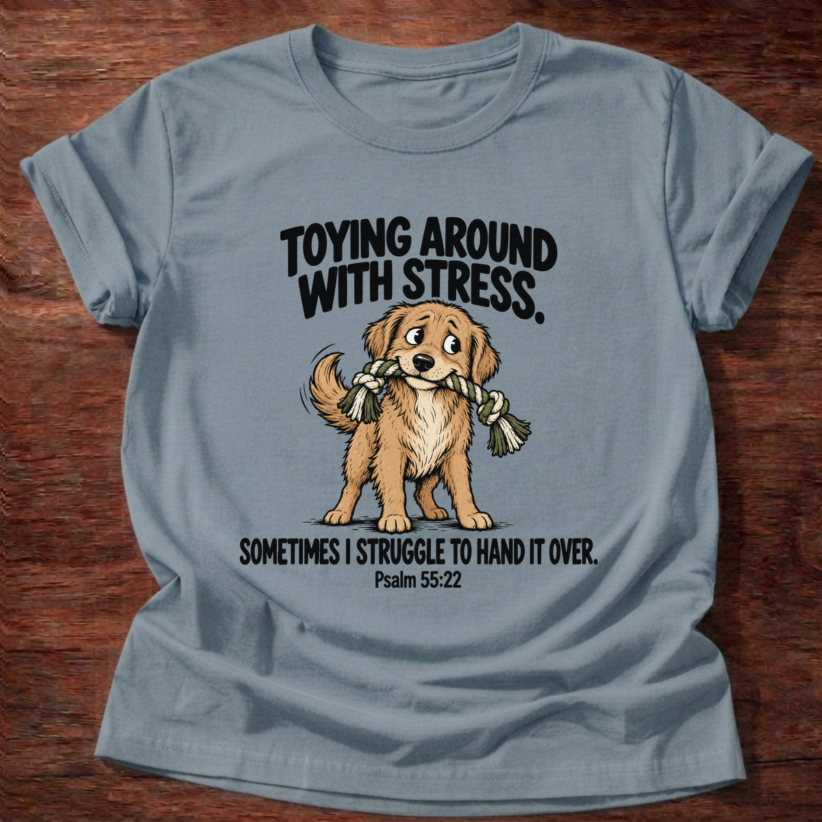 Stone Blue t-shirt printed with a dog tugging a rope toy graphic and 'Toying around with stress. Sometimes I struggle to hand it over.' Psalm 55:22 faith based gift