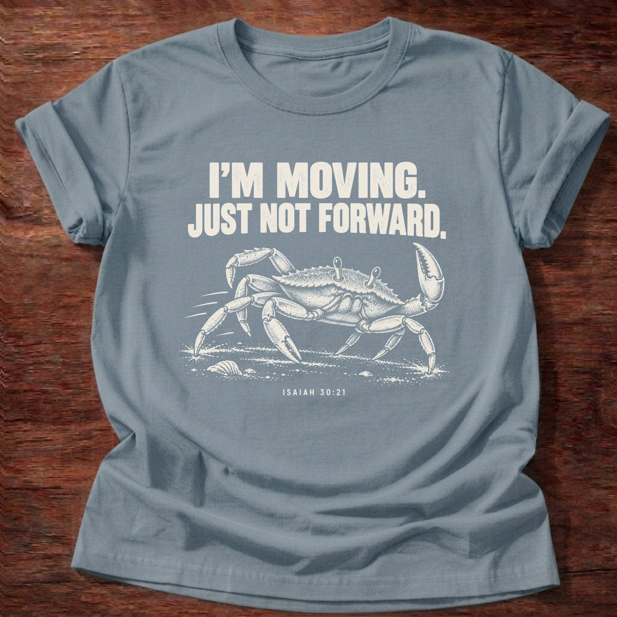 Stone Blue t-shirt printed with a crab scuttling sideways across the sand graphic and 'I'm moving. Just not forward.' Isaiah 30:21 faith based gift