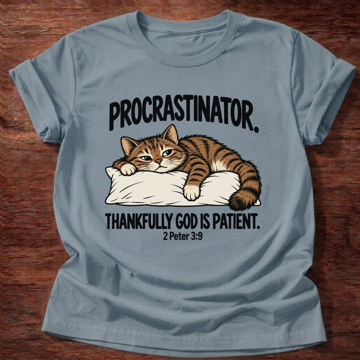 Stone Blue t-shirt printed with a cat sleeping on a pillow graphic and 'Procrastinator. Thankfully God is patient.' 2 Peter 3:9 faith based gift