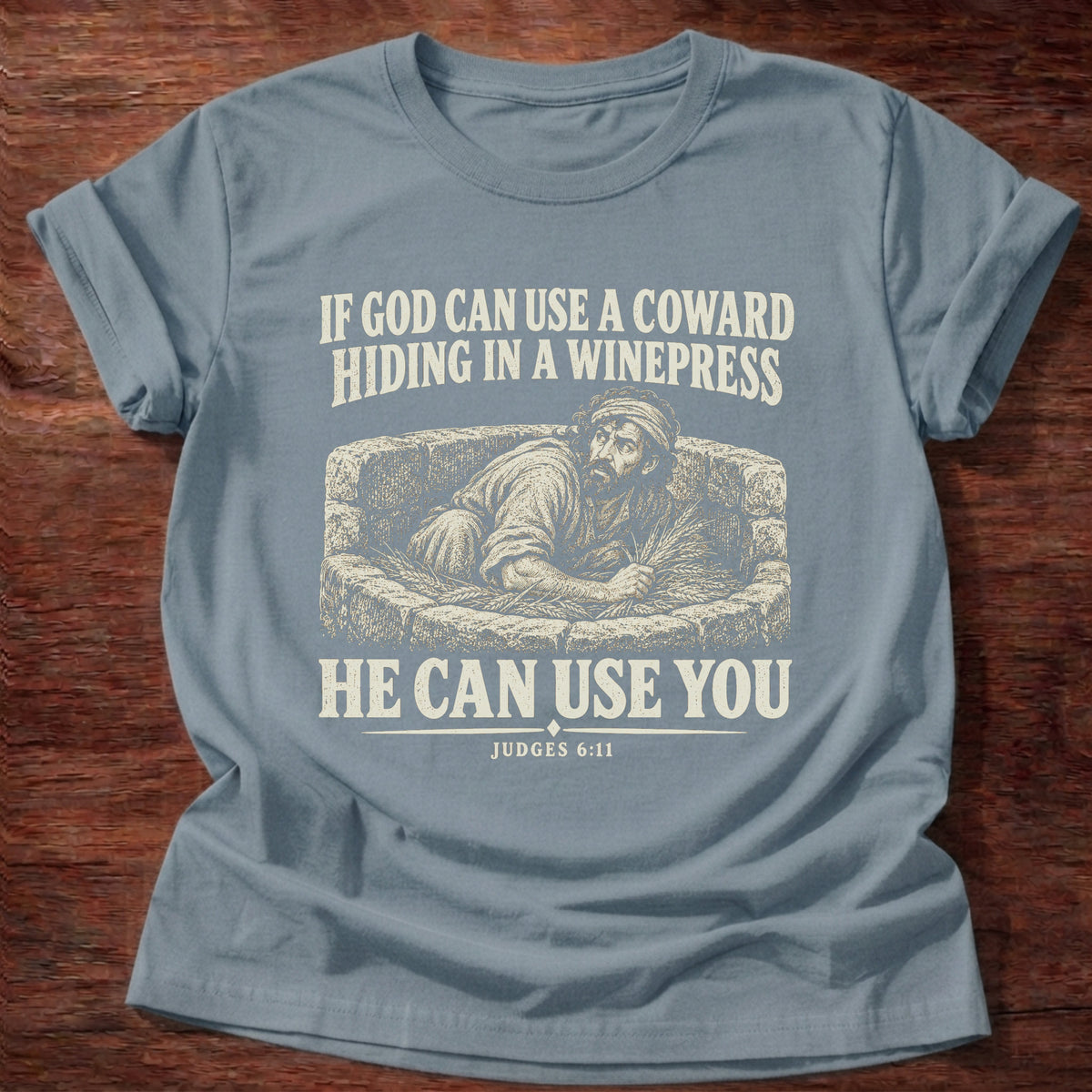 Stone Blue t-shirt printed with Gideon hiding in a winepress graphic and 'If God can use a coward hiding in a winepress, He can use you.' Judges 6:11 faith based gift